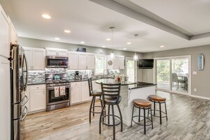 Una cocina moderna con una isla central, taburetes de bar y un comedor con vistas.