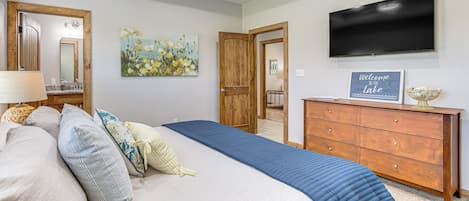 Ein Schlafzimmer mit Bett, Schminktisch, Fernseher und einem Bild an der Wand.