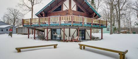 Una cabaña de troncos con balcón, rodeada de nieve.