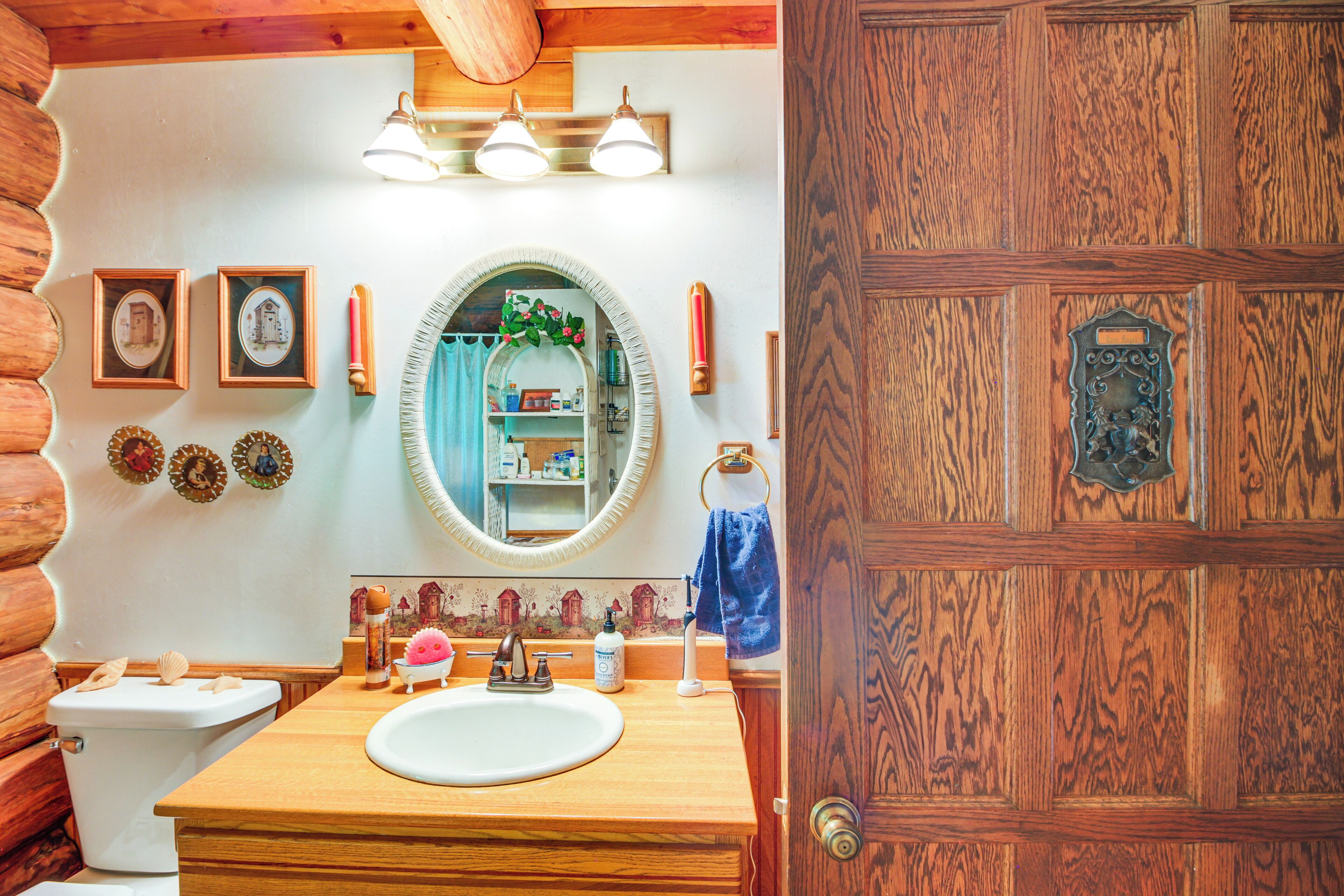 Ein Badezimmer einer Holzhütte mit Waschbecken, Spiegel und Holztür.