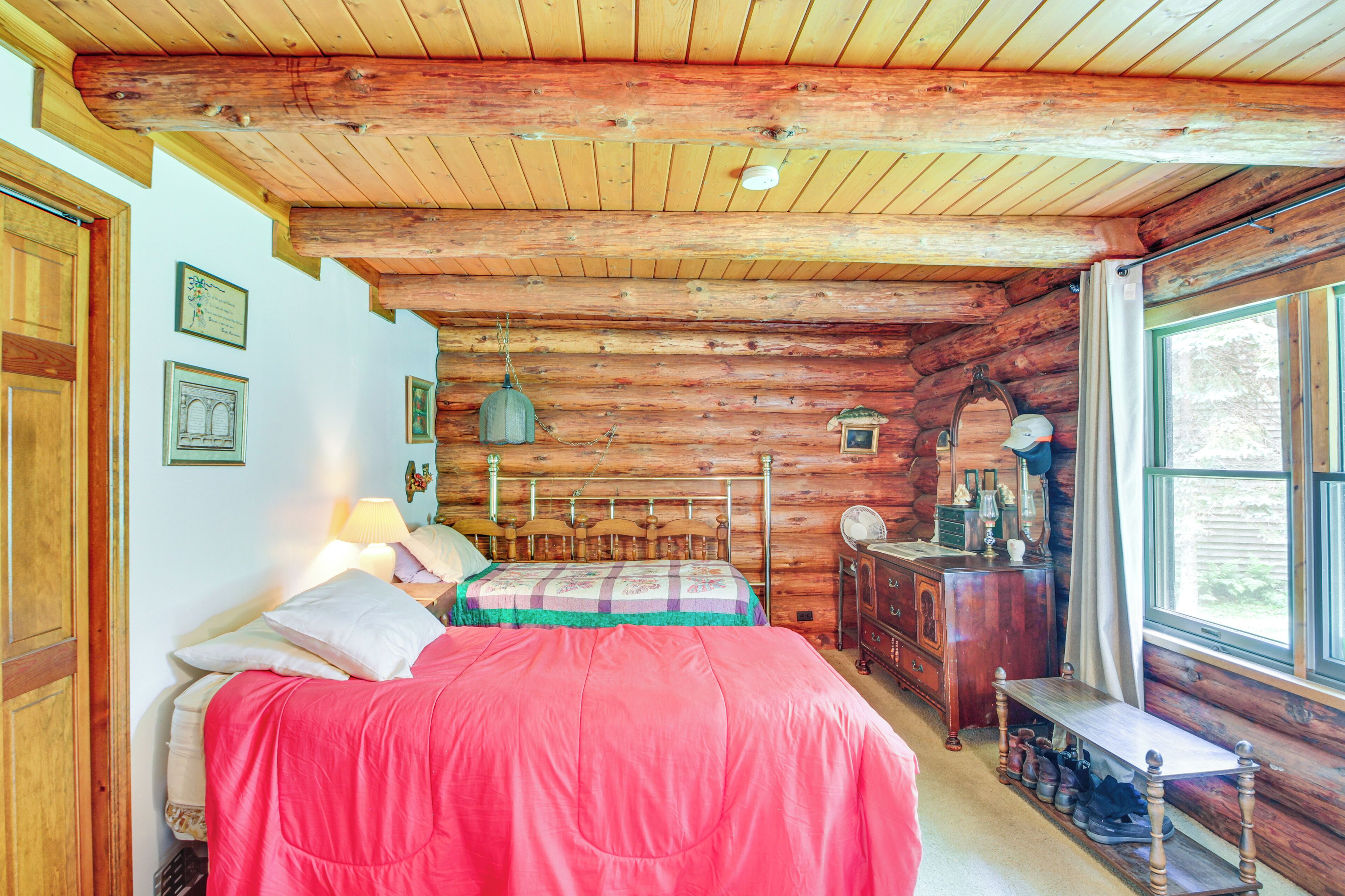 Une chambre dans une cabane en rondins, avec un lit, une commode et une fenêtre.