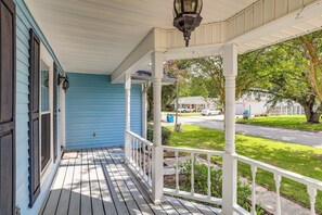 A porch with a white railing, a blue house, and a street view in the background. - 5 Mi to Downtown Morgan City: Waterfront Retreat (Morgan City)