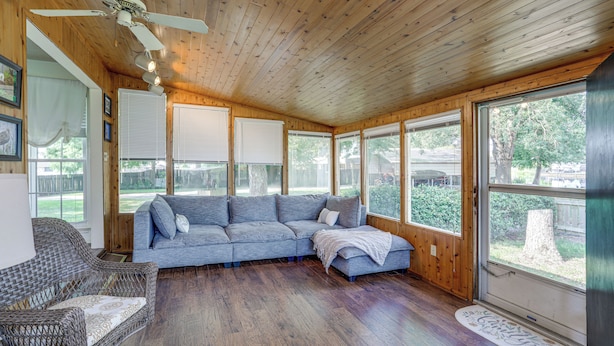 A cozy room with a wooden ceiling, a gray sectional sofa, a wicker chair, and large windows offering views of the outdoors. - 5 Mi to Downtown Morgan City: Waterfront Retreat (Morgan City)