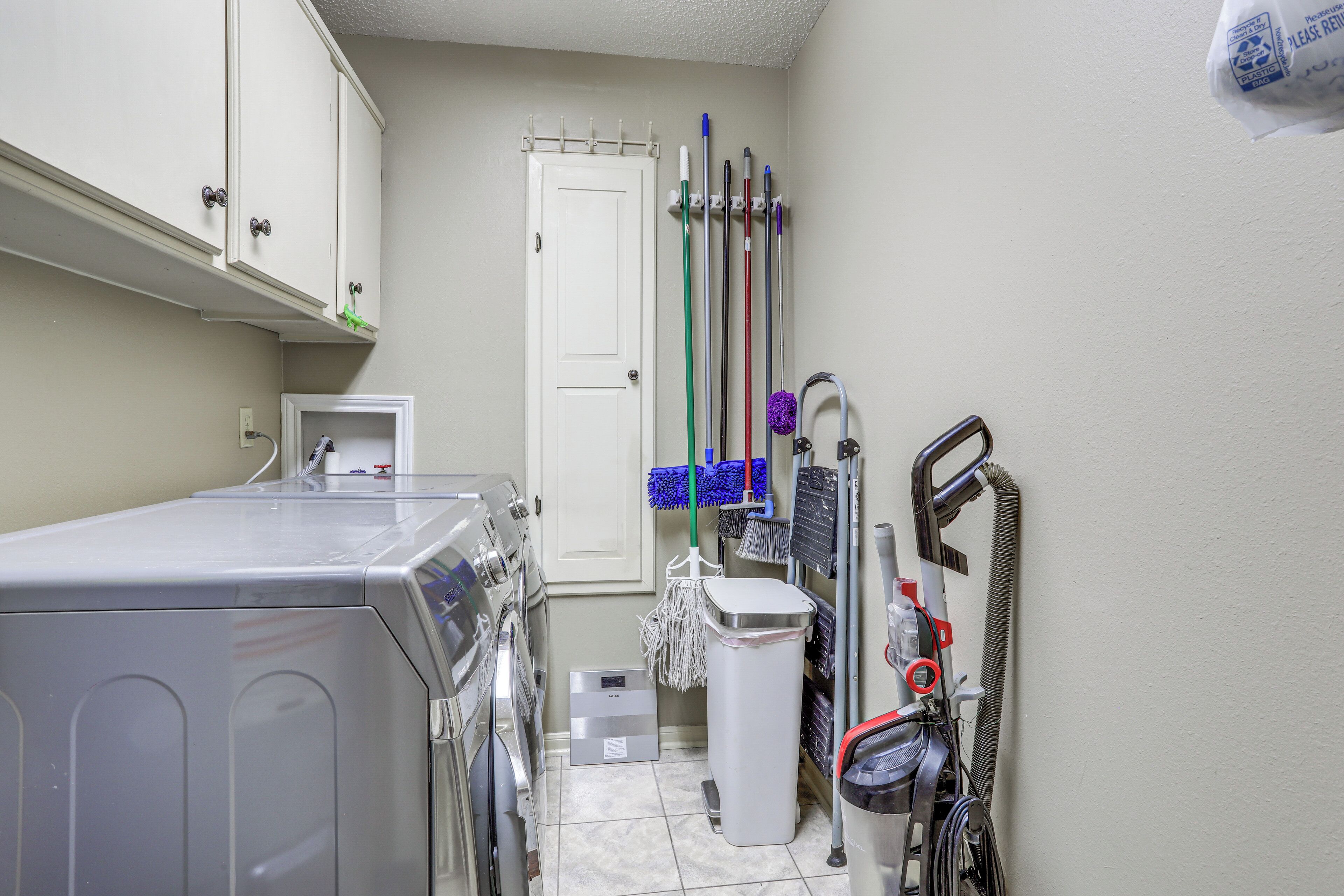 A laundry room with a washing machine, dryer, and a vacuum cleaner.