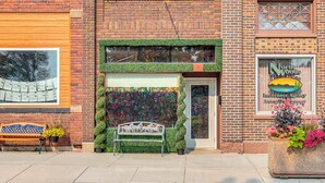 A brick building with a large window, a bench, and a planter with flowers.