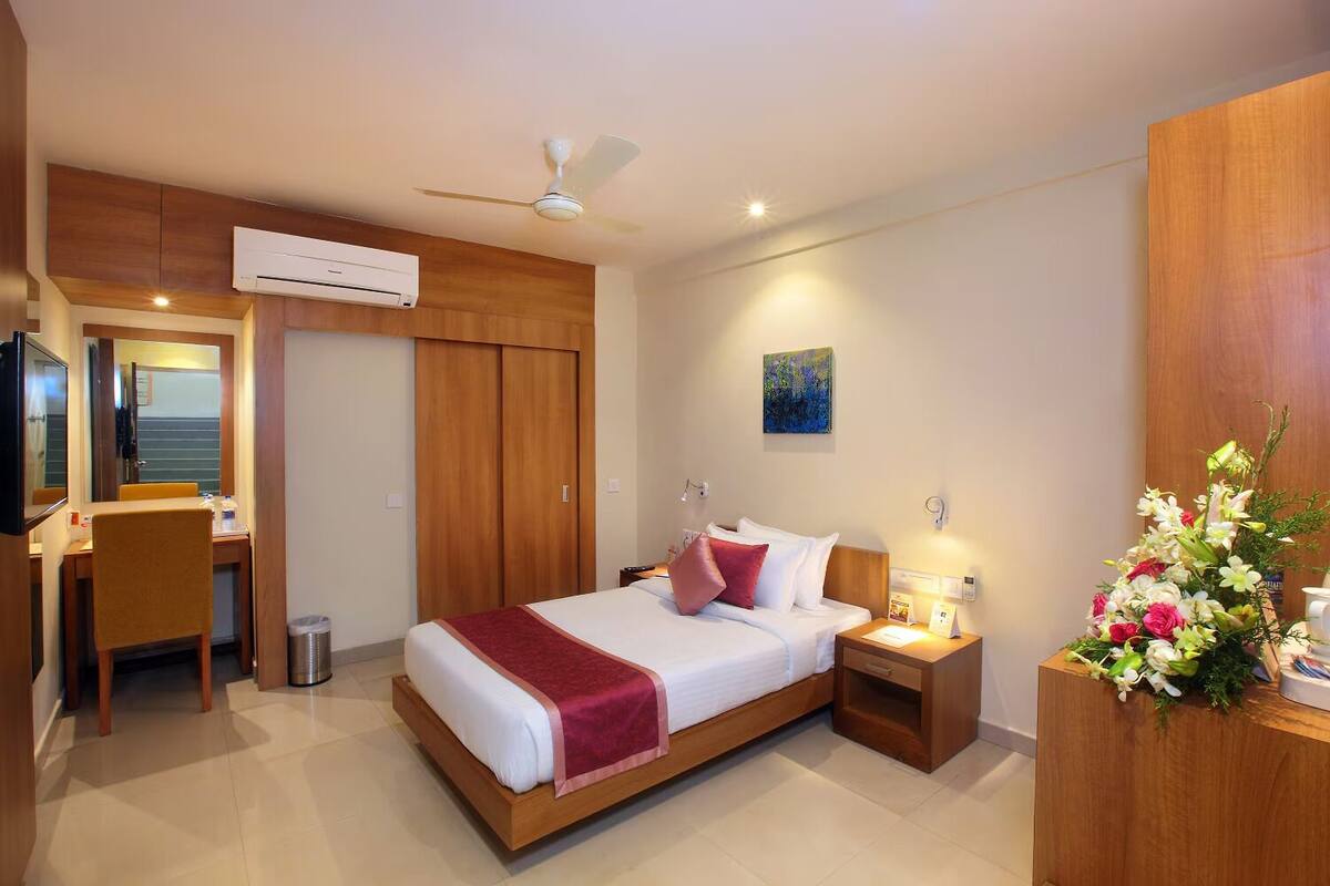 A modern hotel room with a wooden bed, a desk, and a wardrobe.