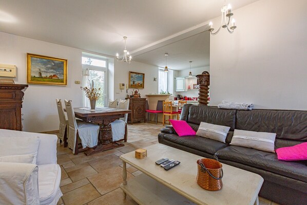 Una sala de estar con sofá, una mesa de comedor y una cocina al fondo.