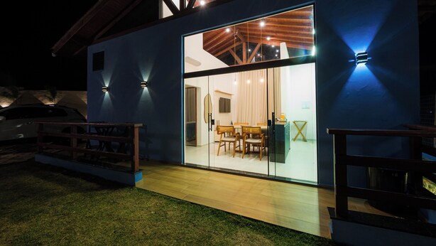 A modern house with a large glass door leading to a dining area. - Chalé Arca da Vida (Piquete)