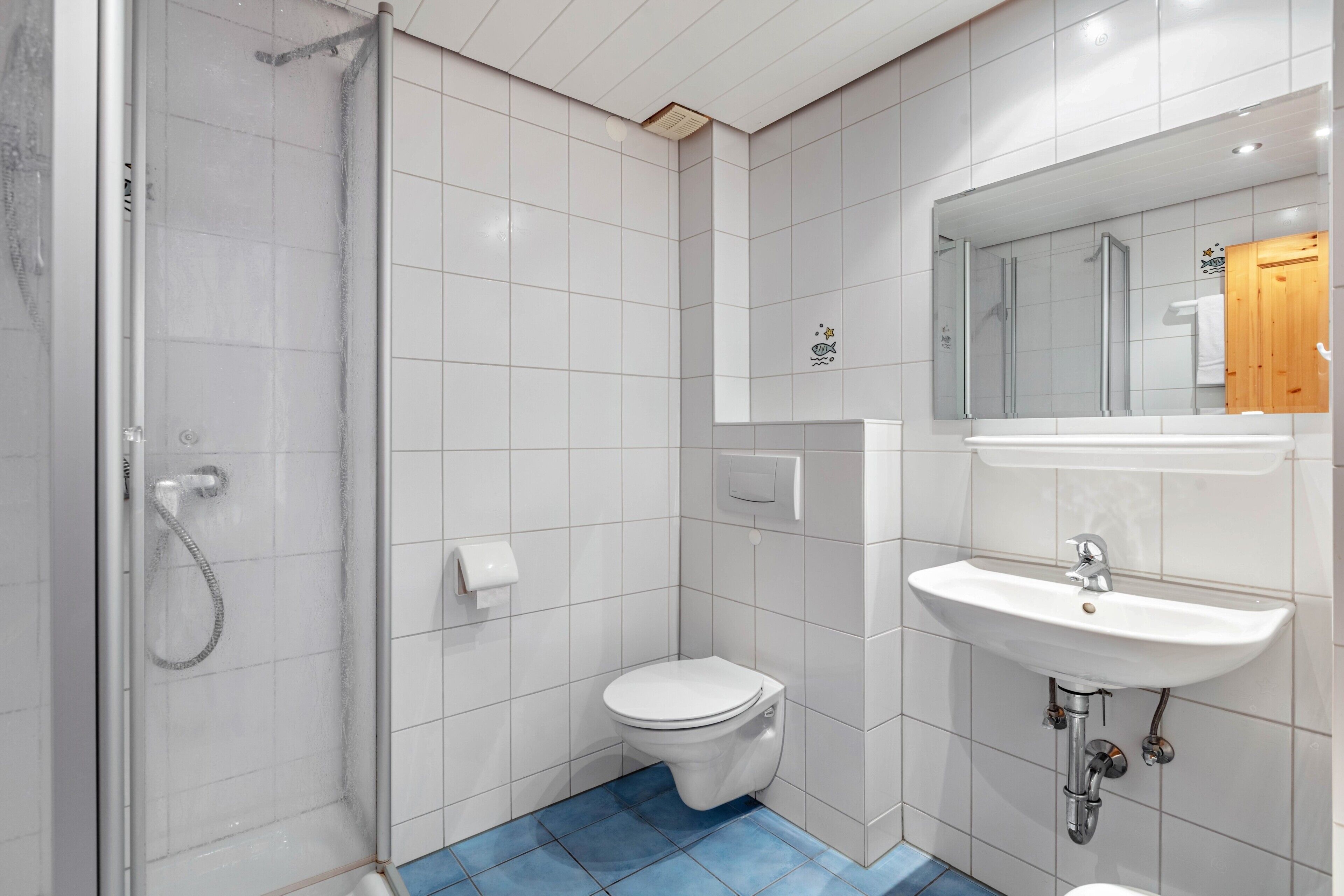 A bathroom with a shower, toilet, sink, and mirror.