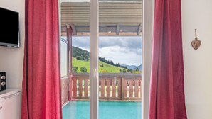 A room with a balcony, a TV, and a radiator. - Holiday Apartment '10' with Mountain View, Shared Terrace and Wi-Fi (Todtnau OT Todtnauberg)