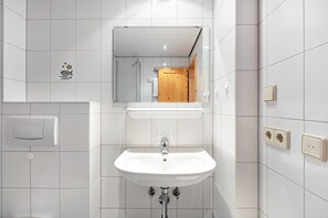 A bathroom with a white sink, a mirror, and a wooden door. - Holiday Apartment '10' with Mountain View, Shared Terrace and Wi-Fi (Todtnau OT Todtnauberg)