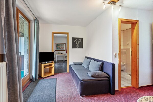 A modern living room with a sofa, television, and artwork on the wall. - Holiday Apartment '10' with Mountain View, Shared Terrace and Wi-Fi (Todtnau OT Todtnauberg)
