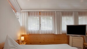 Une chambre d’hôtel avec un lit, une télévision, une table de chevet et une fenêtre avec des rideaux.