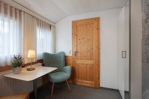 A room with a wooden door, a table with a lamp, a chair, and a potted plant. - Room '16' with Mountain View, Shared Terrace and Wi-Fi (Todtnau OT Todtnauberg)