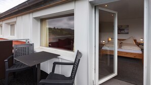 Quarto com cama, janela com vista, mesa e cadeira.