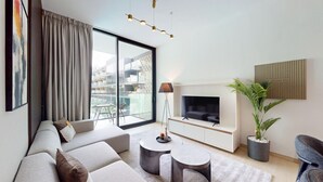 A modern living room with a large TV, comfortable seating, a coffee table, and a balcony with a view. - Binghatti Crescent - Two Bed with Pool View in JVC (Jumeirah Village Circle)