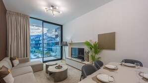 A modern living room with a sofa, coffee table, and dining area set up for a meal. - Binghatti Crescent - Two Bed with Pool View in JVC (Jumeirah Village Circle)