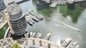 Un hôtel situé au bord de l’eau, avec un bâtiment circulaire, une marina remplie de bateaux et un pont en arrière-plan.