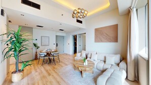 Uma sala de estar moderna com sofá, mesa de centro, mesa de jantar e uma planta grande.
