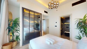 Quarto de hotel moderno com cama grande, closet espaçoso e banheiro com chuveiro e pia.