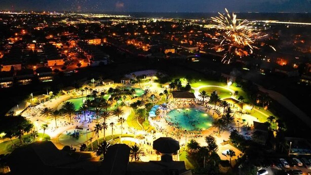 A resort with a large pool area, multiple palm trees, and a fireworks display in the background. - Luxury 5 bedroom Resort Villa Pool,Spa,Game Room (Davenport)
