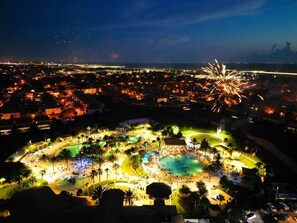 A resort with a large pool area, multiple palm trees, and a fireworks display in the background. - Luxury 5 bedroom Resort Villa Pool,Spa,Game Room (Davenport)
