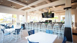 A restaurant with outdoor seating, a bar area, and a television screen. - Luxury 5 bedroom Resort Villa Pool,Spa,Game Room (Davenport)
