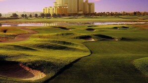 A golf course with bunkers, a water body, and a hotel in the background. - Luxury 5 bedroom Resort Villa Pool,Spa,Game Room (Davenport)