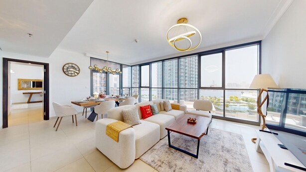 A modern living room with a sofa, coffee table, and dining area.