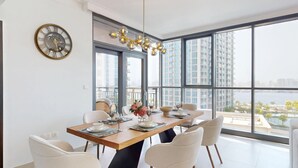 A modern dining room with a large table set for six, large windows offering a city view, and a decorative clock on the wall.