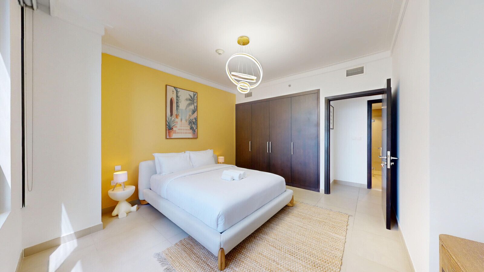 A modern bedroom with a large bed, a wardrobe, and a painting on the wall.
