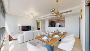 A modern dining area with a wooden table set for six, surrounded by white chairs.