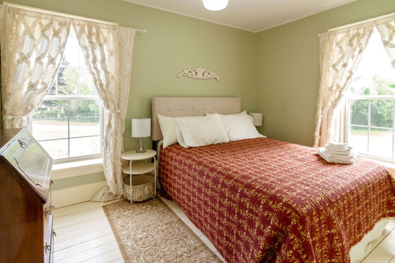 A bedroom with a bed, a nightstand, a lamp, and a window with curtains.