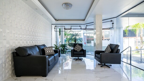 A modern living room with a black leather sofa, a black armchair, and a glass coffee table.