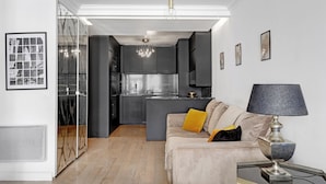 A modern living room with a sofa, a lamp, and a dining table. - Stylish 2BR Near Faubourg Saint-Honoré (Paris)