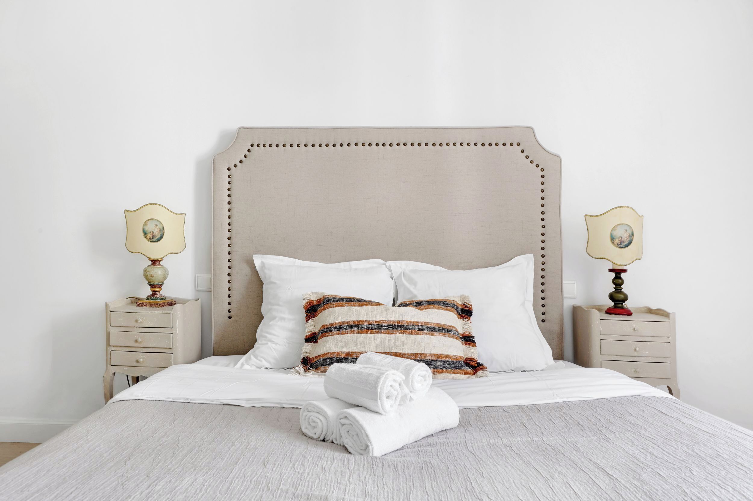 Un lit bien fait, avec des draps blancs, des oreillers à rayures et des serviettes enroulées.