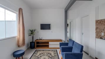 Una sala de estar moderna con un sofá, una mesa de centro, un televisor montado en la pared y una planta en maceta.