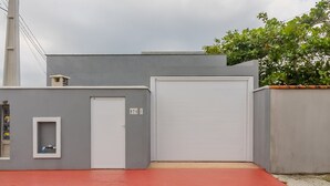Ein graues Gebäude mit einer weißen Garagentür, einem kleinen Fenster und einer roten Rampe, die zum Eingang führt.