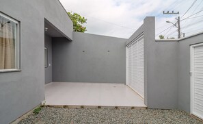 Un patio moderno y minimalista con suelo de hormigón, rodeado de paredes grises y una pequeña zona de grava.