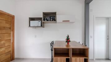A modern room with a wooden table, a small Christmas tree, and built-in shelves with kitchen appliances.