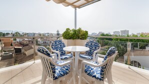 A balcony with a table and chairs, a potted plant, and a view of the cityscape. - Apartment 'Las Palmeras 2' with Shared Pool, Wi-Fi and Air Conditioning (Cala Millor)