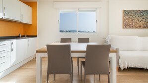 A modern kitchen with white cabinets, a dining table with four chairs, and a large window with a view. - Apartment 'Las Palmeras 2' with Shared Pool, Wi-Fi and Air Conditioning (Cala Millor)