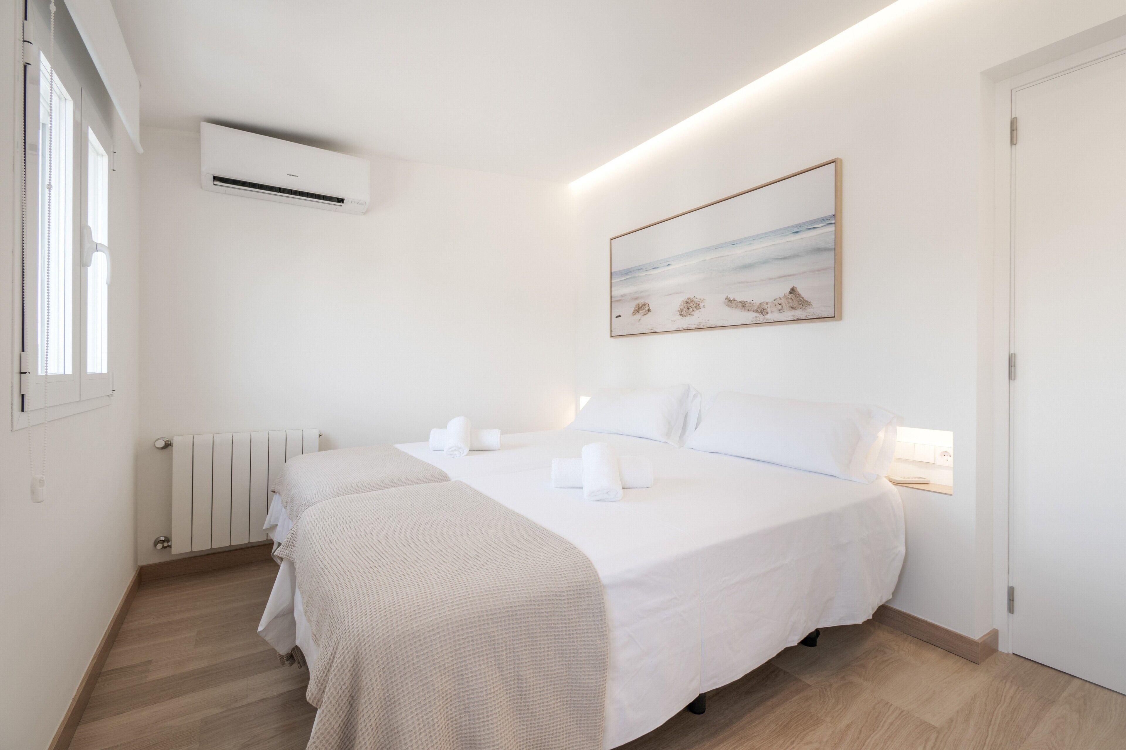 Habitación de hotel con una cama, un radiador, un equipo de aire acondicionado y un cuadro en la pared.
