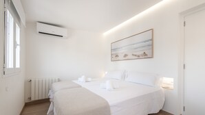 A hotel room with a bed, a radiator, an air conditioning unit, and a painting on the wall. - Apartment 'Las Palmeras 2' with Shared Pool, Wi-Fi and Air Conditioning (Cala Millor)