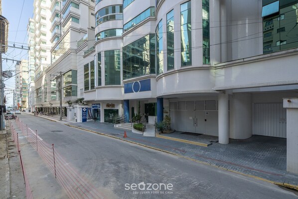 A modern hotel with a curved facade, large windows, and a blue sign.