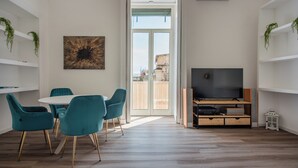 A modern living room with a dining area, a TV, and a balcony with a view.
