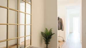 A hallway with a large mirror, a potted plant, and a bench.