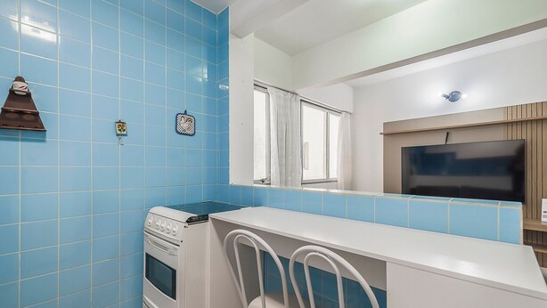 Una cocina con baldosas azules, una estufa blanca y una silla blanca.