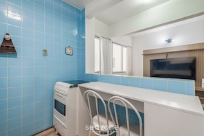 A kitchen with blue tiles, a white stove, and a white chair. - Well-located ap in Beachfront Condominium Iptr0171 (Balneário Camboriú)