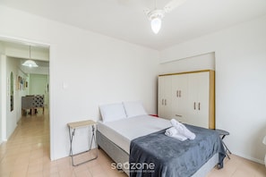 A bedroom with a bed, bedside table, wardrobe, and a small table with a chair. - Well-located ap in Beachfront Condominium Iptr0171 (Balneário Camboriú)